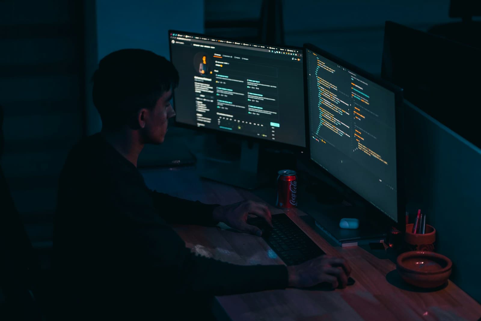 Young developer writing full-stack code on dual monitors